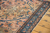 Worn side of an antique Persian Lilihan rug, with blush rose field and intricate indigo floral motifs.