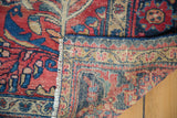 Folded edge of vintage Lilihan rug reveals hand-knotted structure and distressed pile.