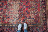 Distressed Lilihan rug, cherry red field with navy blue floral vines, aged texture, with feet.