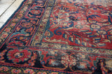 Distressed hand-knotted Lilihan rug detail showing cherry red field, navy floral vines, and gold border.