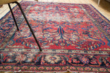 Localized heavy distress across the cherry red Lilihan rug field with navy and gold patterns.