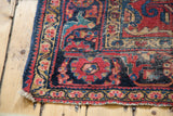 Distressed Lilihan rug corner with red and navy floral borders and secured fringe.