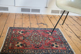Cherry red field and dark navy border of a vintage Lilihan rug, showing floral spandrels.