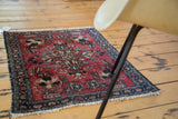 Lilihan rug corner, cherry red field, dark navy spandrels with intricate floral vinery, white fringe.