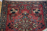 Blossoming floral motif in navy, bronze, teal on cherry red Lilihan rug, wear to knot heads.