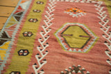 Blush red and lime green geometric patterns with light blue accents on a hand-woven Kilim.