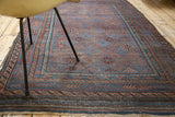Distressed indigo and bronze gul field with reciprocating wave border of antique Belouch rug.