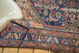 Intricate, distressed border of a Persian Malayer rug, showcasing rust, navy, and salmon hues.
