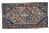 Distressed Antique Hamadan rug featuring an indigo blue serrated medallion and beige field with terra cotta.