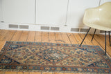 Distressed central diamond medallion and geometric patterns in blue, beige, and terracotta.