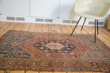 Distressed antique Persian Malayer rug with rich deep blue medallion and terracotta field.