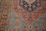 Distressed antique Malayer rug's geometric patterns in rust, indigo, and dusty teal.