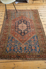 Antique Malayer rug's fringed corner, highlighting distressed red, blue, and beige geometric motifs.