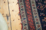 Distressed selvage and intricate floral border of an antique Persian Malayer rug in indigo and ruby.