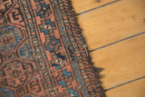 Antique Belouch runner's secured edge, with indigo, bronze, and chestnut gul motifs.