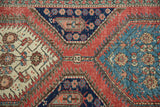 Vibrant geometric diamond motif with serrated edges on a distressed antique Persian rug.