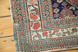 Distressed antique Persian rug fragment border, with colorful floral patterns and fringe.