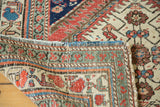 Folded edge of distressed antique Northwest Persian rug, showing mint green and blush rose border.