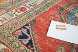 Distressed brick red field, deep blue medallion with serrated perimeter, and floral border.