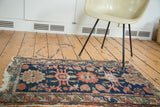 Distressed antique Lilihan rug: salmon floral design, worn navy pile, tattered fringe.