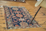 Distressed antique Lilihan rug in navy with faded salmon and celadon floral motifs.