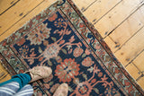 Distressed antique Lilihan rug: navy field, salmon, celadon crab floral design, contoured edge.
