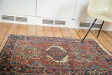 Distressed antique Karaja rug displaying geometric motifs in brick red, navy, and teal.