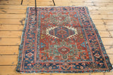 Distressed texture of brick red Karaja rug with geometric navy, teal, and ivory medallion.
