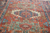 Distressed brick red, teal, and ivory rectilinear patterns of an antique Karaja rug.