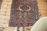 Distressed antique Karaja rug corner with brick red, navy geometric motifs and fringe.