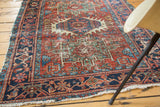 Distressed antique Karaja rug's geometric navy border, brick red field, teal details, and secure fringe.