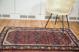 Corner of vintage Engelas rug displaying geometric cherry red field and lavender azure border.