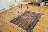 Angled view of the antique Lilihan rug, showing distressed cranberry field and geometric celadon green.