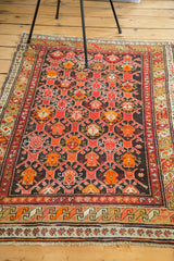Vintage Caucasian rug's vibrant geometric pattern with tiger orange, crimson red, and charcoal.