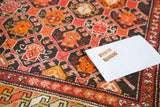 Geometric pattern on a hand-knotted vintage Caucasian rug in tiger orange and crimson.