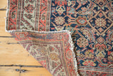 Folded corner of antique Malayer rug, revealing hand-knotted foundation and distressed pile.