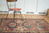 Distressed antique Soumac rug field showing heavy wear, geometric cobalt blue and red.