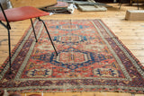 Distressed texture on an antique Soumac Caucasian rug with geometric patterns in red, blue, and tangerine.