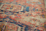 Distressed texture of hand-woven Soumac rug with geometric cobalt and red patterns.