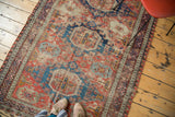 Heavily distressed antique Soumac rug texture, geometric patterns in faded red and cobalt blue.