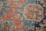 Distressed geometric patterns of a Caucasian Soumac rug, featuring aged red and cobalt blue tones with tangerine hints.