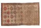 Antique Belouch rug with geometric patterns in ivory, muted gold, and fiery red-orange patina, 2'3