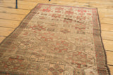 Aesthetic wear and geometric patterns in muted gold and red-orange on an antique Belouch rug.