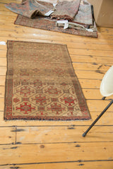 Geometric motifs in muted gold and red-orange with dark fringe on an antique Belouch rug.