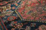 Detail of a distressed antique Halvaie Bijar rug, showing worn crimson and navy blue motifs.