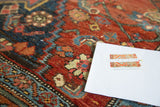 Textured wool pile of antique Bijar rug, featuring bold crimson and navy blue motifs.
