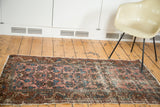 Close-up of distressed Lilihan rug's faded raspberry field with softened blue and bronze motifs.