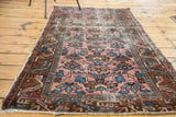 Corner detail of distressed antique Lilihan rug showing faded raspberry field and softened blue motifs.