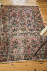 Antique Lilihan rug corner showcasing even distressed texture, varied blue, raspberry tones, and fringe.