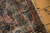 Distressed pile texture of antique Lilihan rug, revealing faded blush, blue, and brown motifs near fringe.